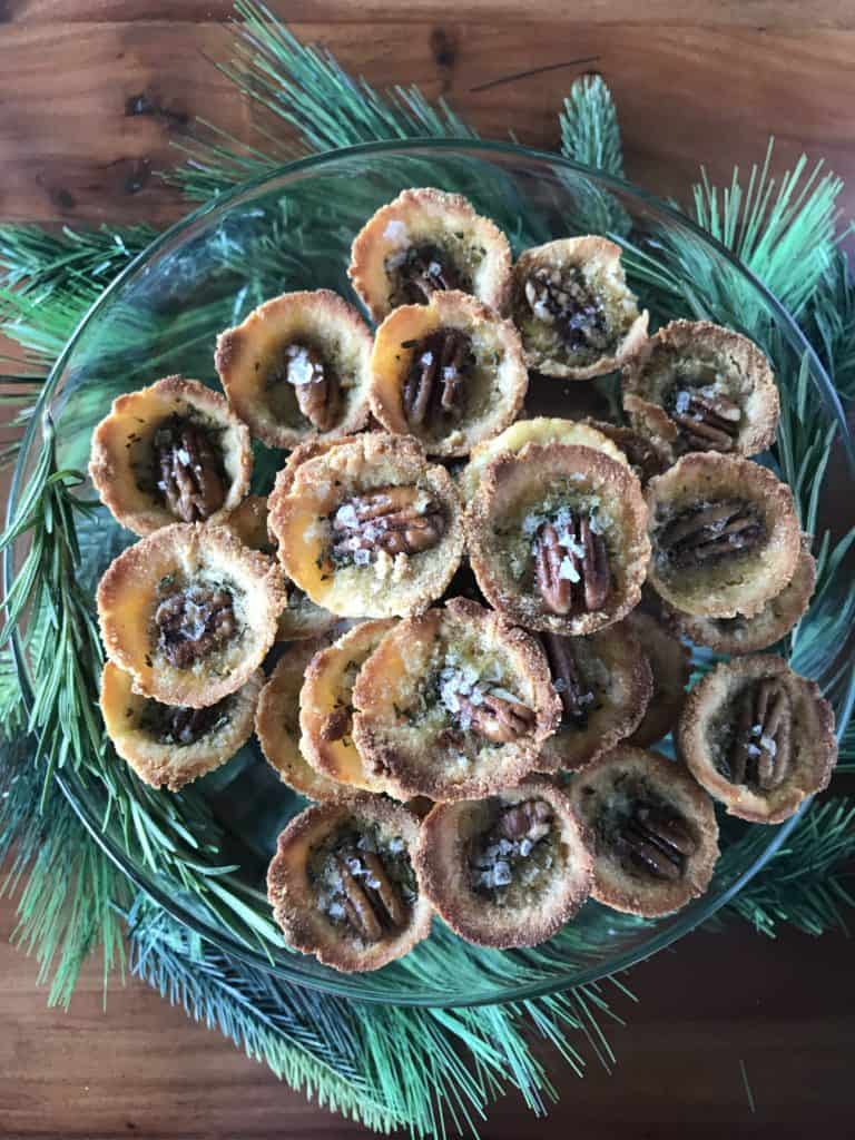 Mini Salted Rosemary Rum Pecan Pies on a platter surrounded by garland