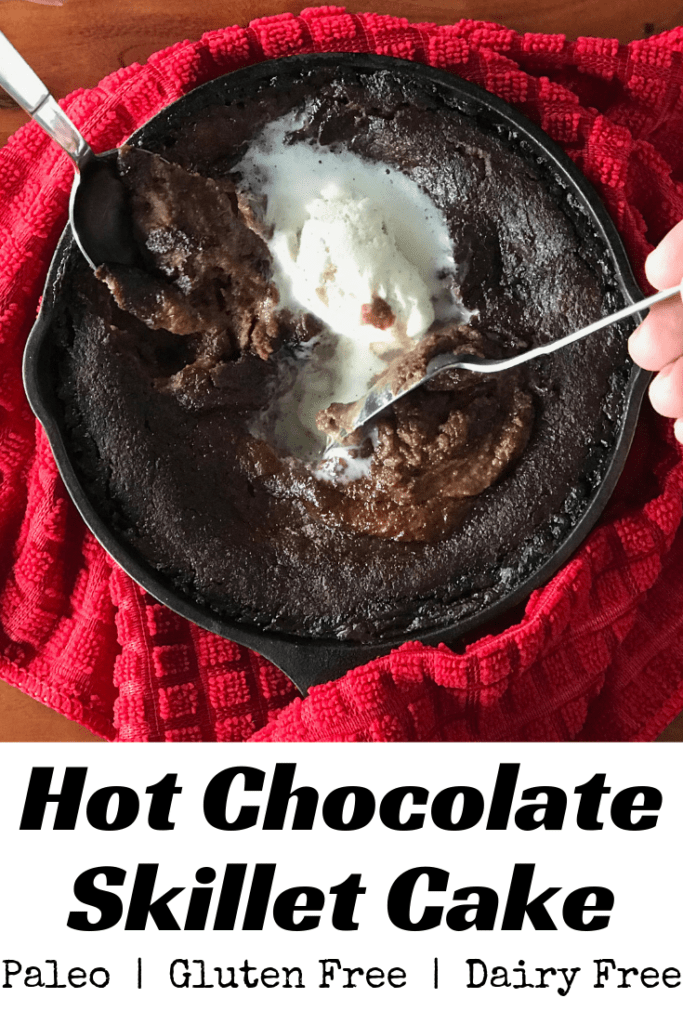Hot Chocolate Skillet Cake wrapped in a red towel and topped with ice cream with two spoons digging in.