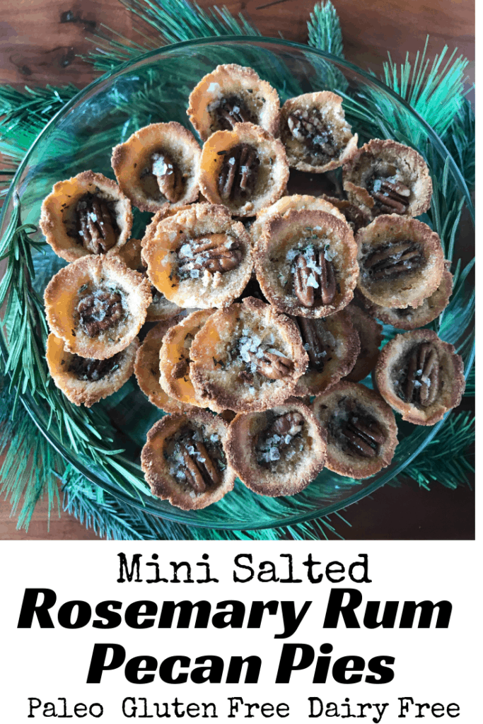 Mini Salted Rosemary Rum Pecan Pies on a glass plate on a wooden table surrounded by pine garland