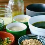 10 flavor boosters you can make while dinner is cooking in various bowls and jars on a wooden table