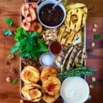 Grilled Fruit Platter with 2 Luscious Sauces on a silver tray on a wooden table surrounded by nuts and fresh mint