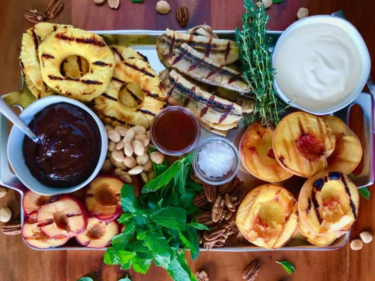 Grilled Fruit Platter with 2 Luscious Sauces on a silver tray on a wooden table surrounded by nuts and fresh mint