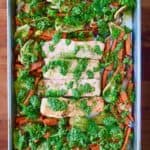 Sheet Pan Lemon Salmon with Pesto on a baking sheet, all on a wooden table