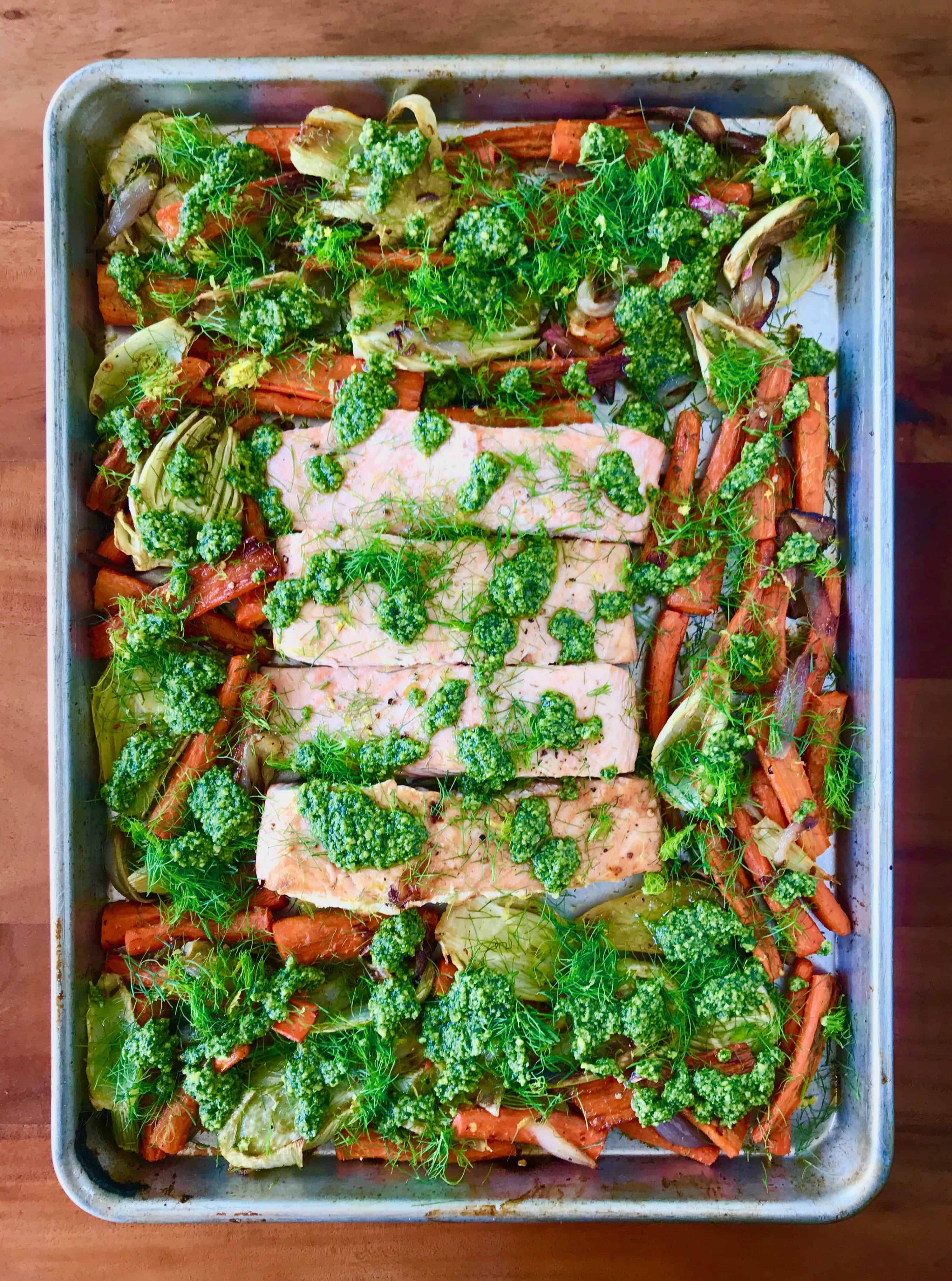 Sheet Pan Lemon Salmon with Pesto on a baking sheet, all on a wooden table