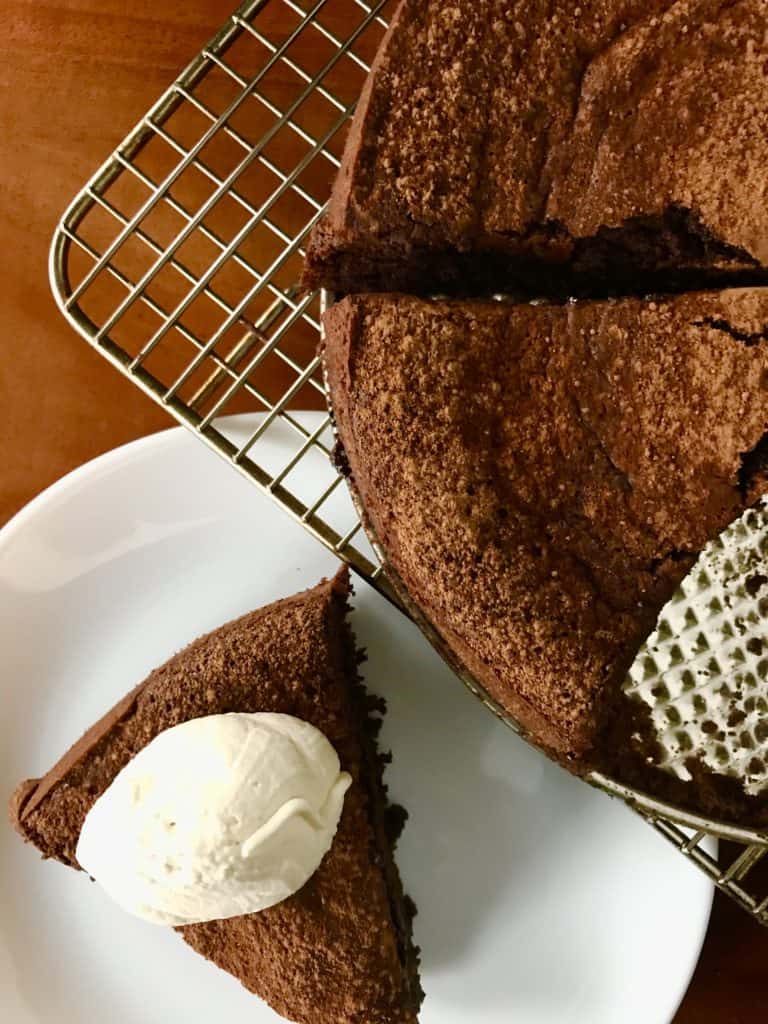 Flourless Chocolate Espresso Cake with Kahlua Whipped Cream on a white plate on a wooden table
