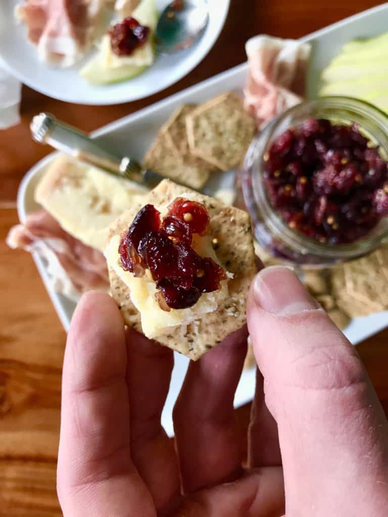 A closeup of cranberry chutney on a cracker with cheese