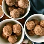 paleo meatballs in white bowls next to blue napkins and little glass bowls of spices, all on a wooden table