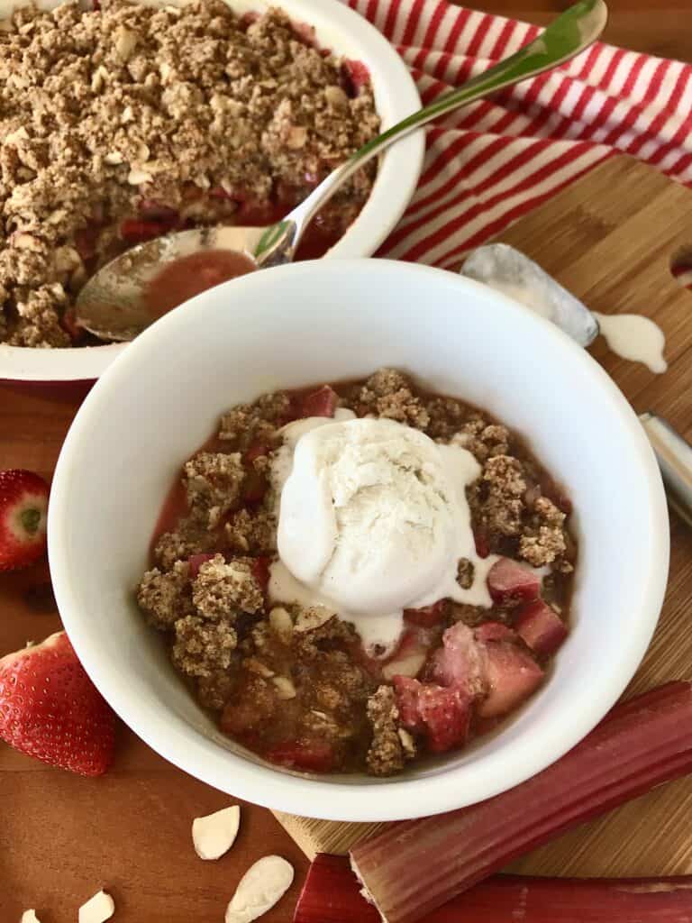 strawberry rhubarb crisp in a baking dish and in a bowl topped with ice cream