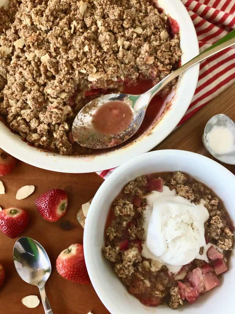 A strawberry rhubarb crisp recipe served in a baking dish and in a bowl with vanilla ice cream