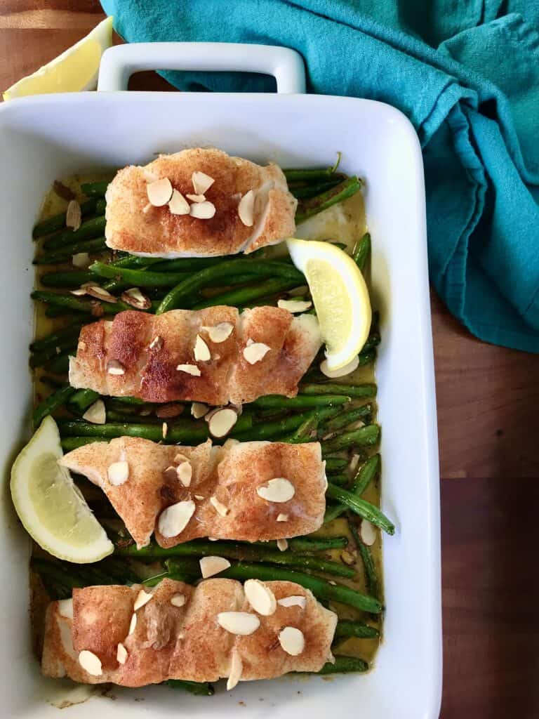 One pan healthy cod baked in a white dish on top of green beans