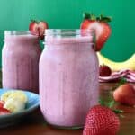 banana smoothie made with strawberries, yogurt and milk in a glass mason jar