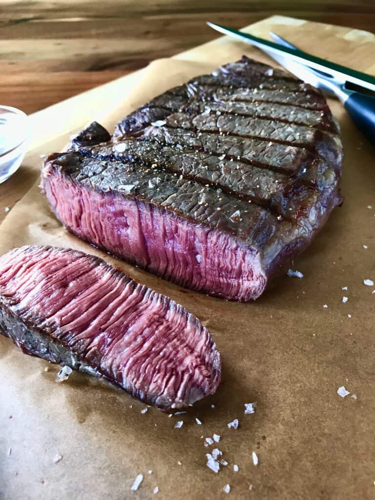 Sliced grilled steak on parchment paper on a cutting board