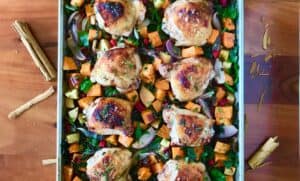 apple chicken with sweet potatoes and chard on a baking sheet on a wooden table