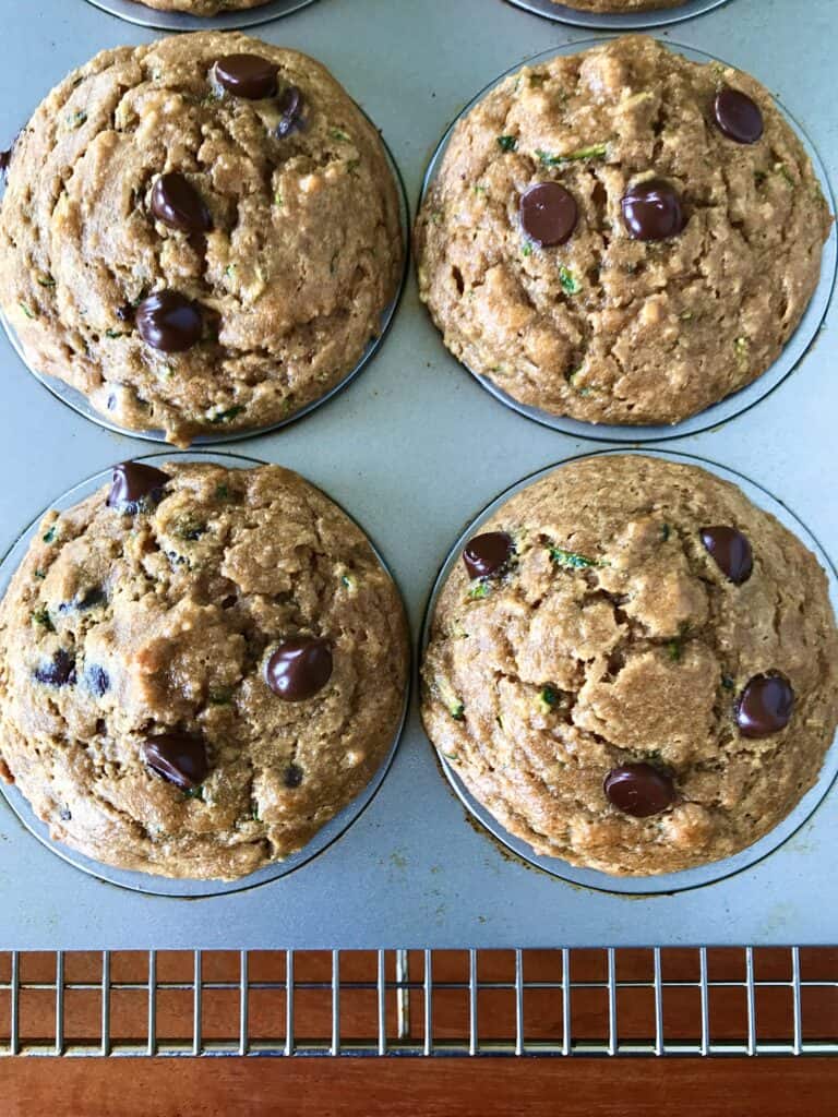 healthy zucchini muffins with chocolate chips in a muffin pan on a cooling rack