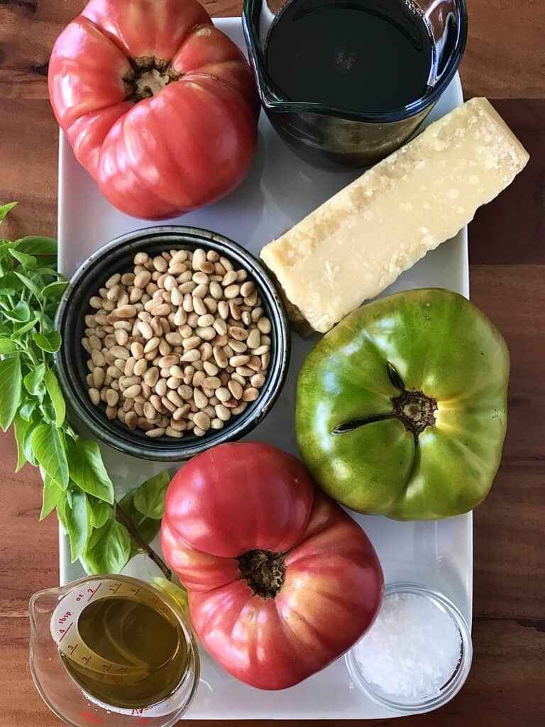 tomatoes, basil, balsamic, salt, olive oil, pint nuts and Parmesan, all on a white platter