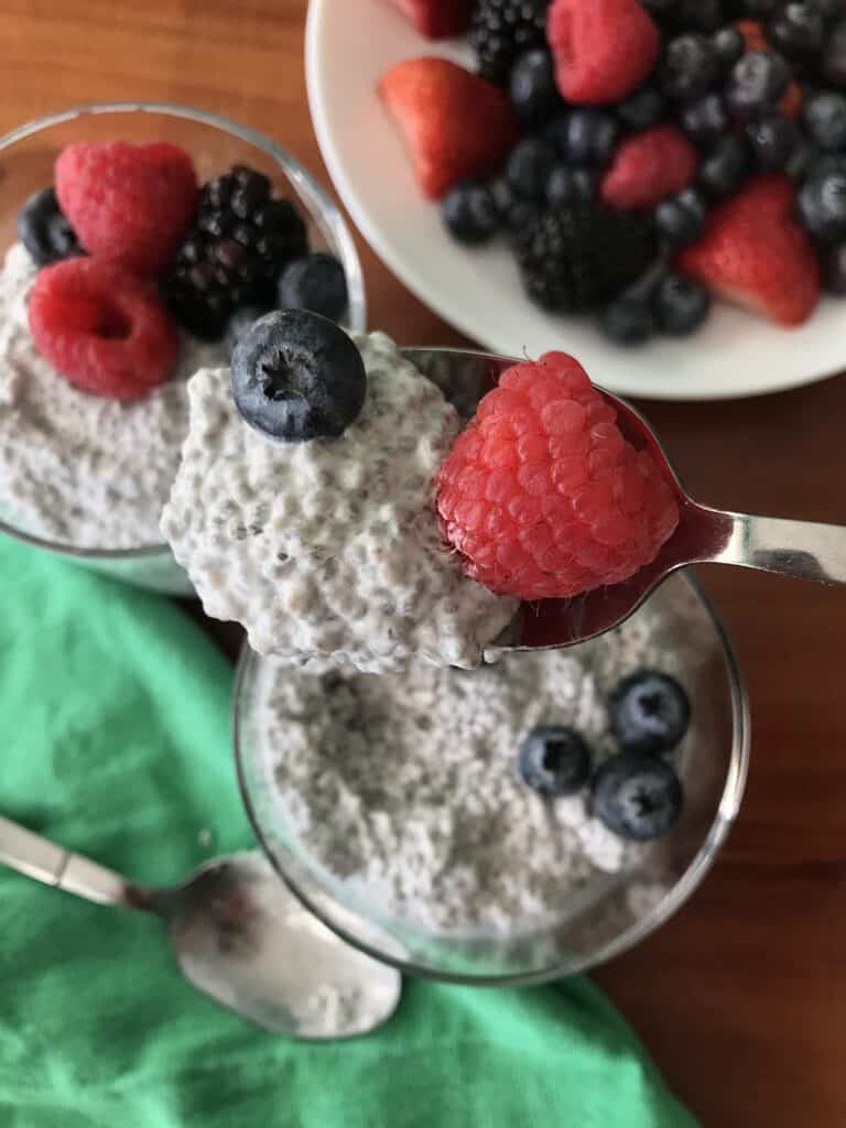 coconut chia pudding on a spoon with berries