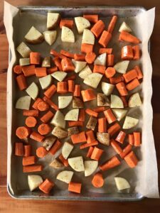 chopped potatoes and carrots on a parchment-lined baking sheet