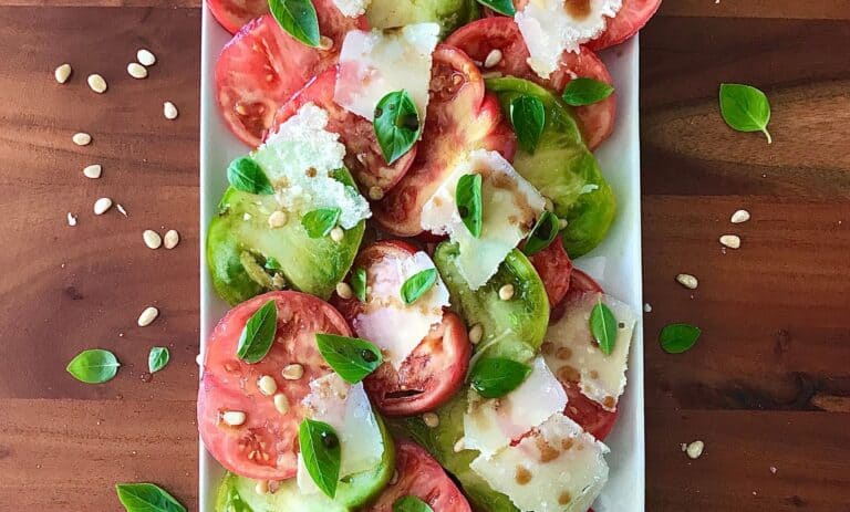 tomato basil salad with balsamic and Parmesan on a white platter