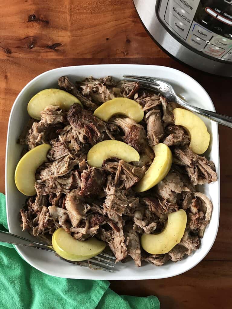Whole30 pulled pork cooked with apple cider in a white dish with 2 forks