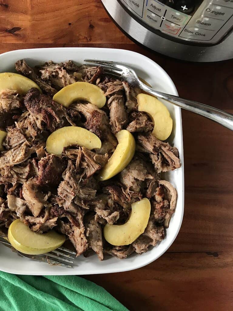 the best pulled pork in a white dish with 2 forks