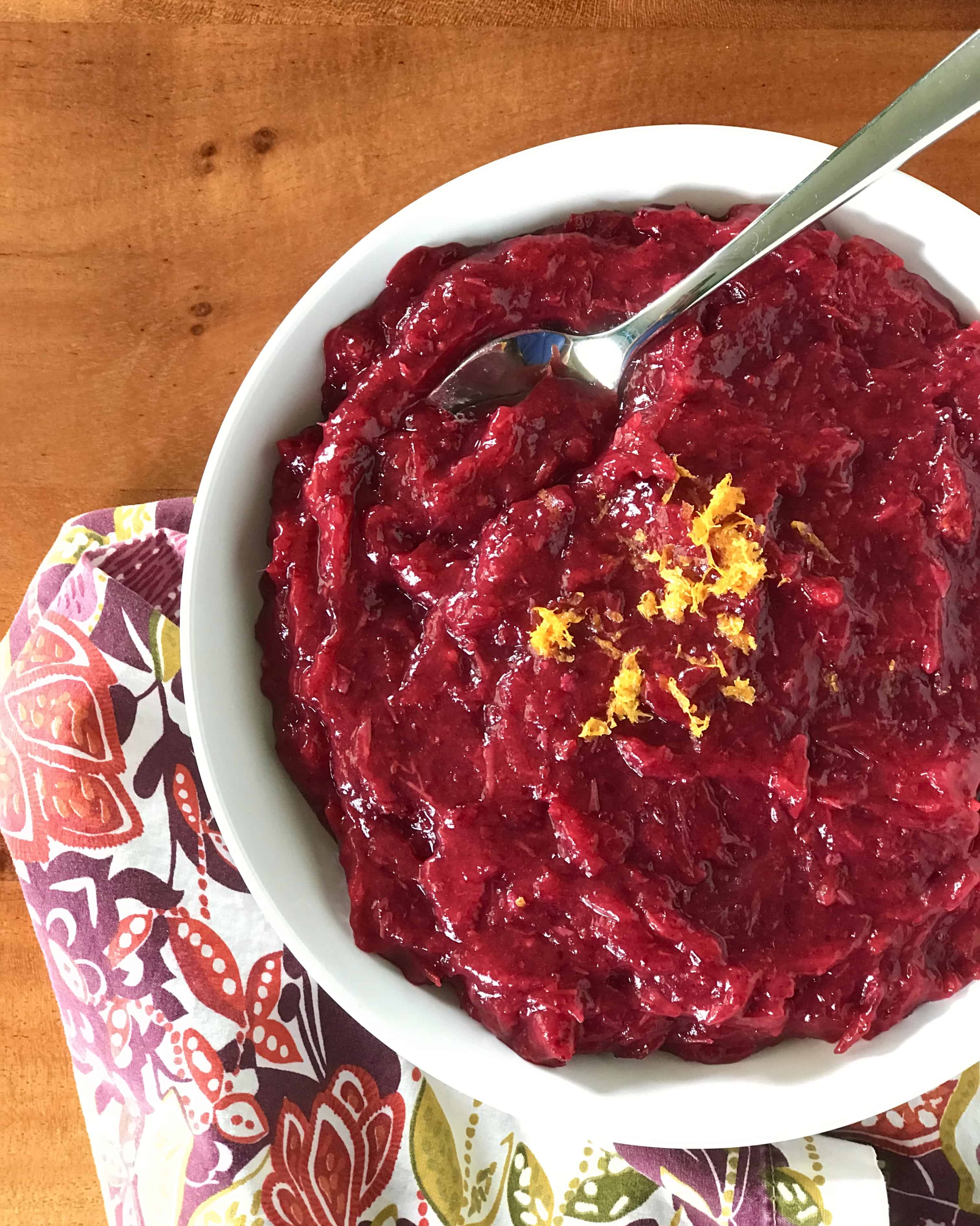 healthy cranberry sauce in a white bowl next to a floral napkin