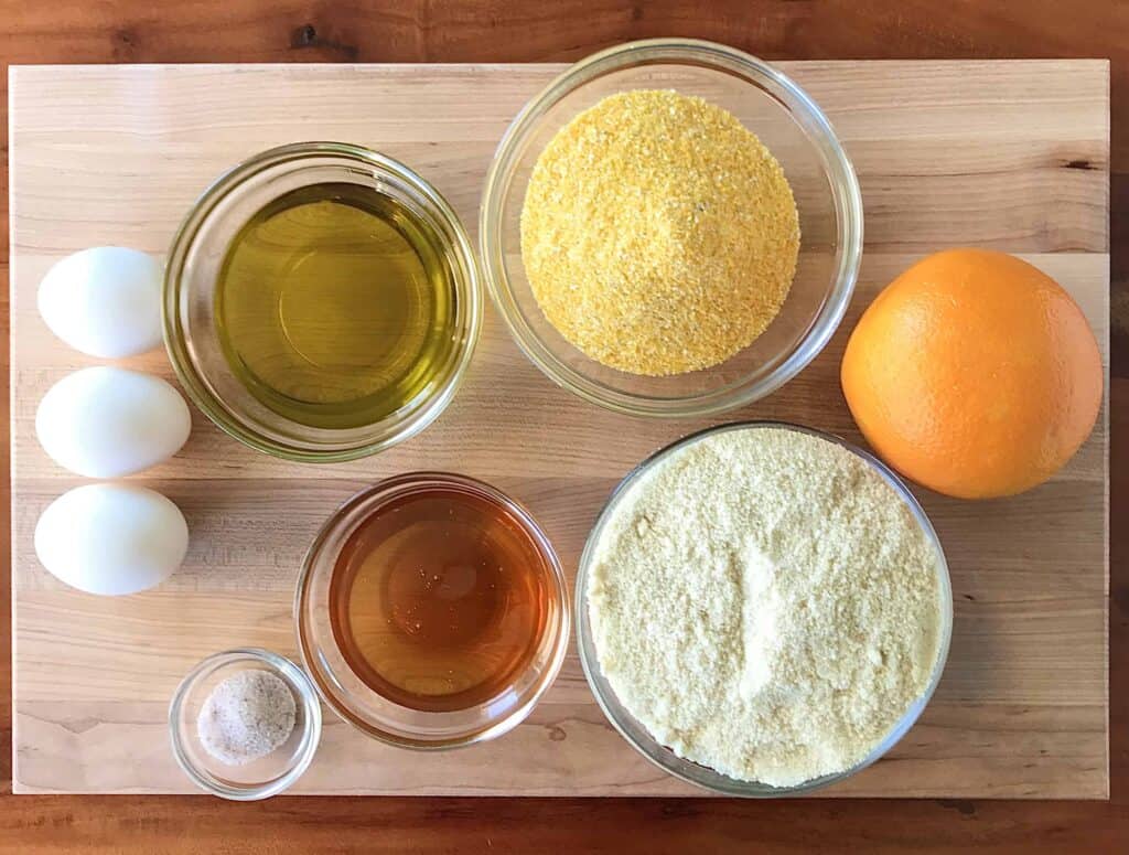 Ingredients for an Italian cake: cornmeal, almond flour, honey, olive oil, an orange, and eggs