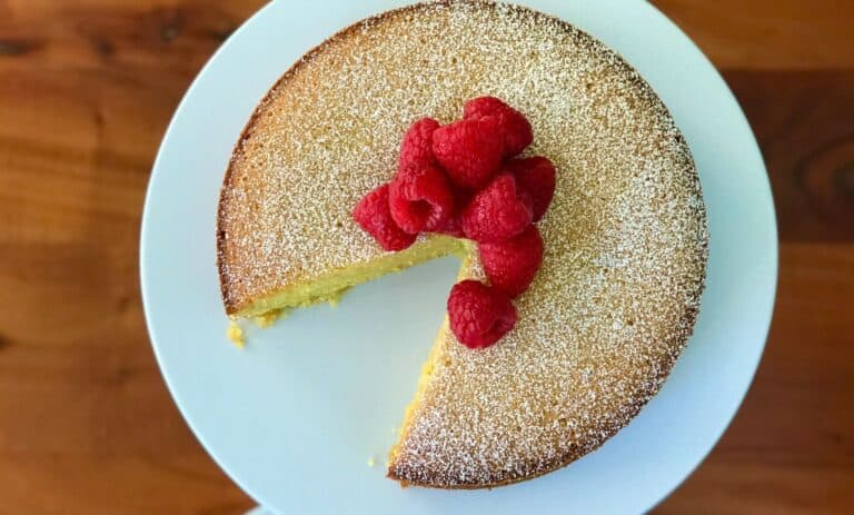 Italian cornmeal cake on a white platter topped with raspberries