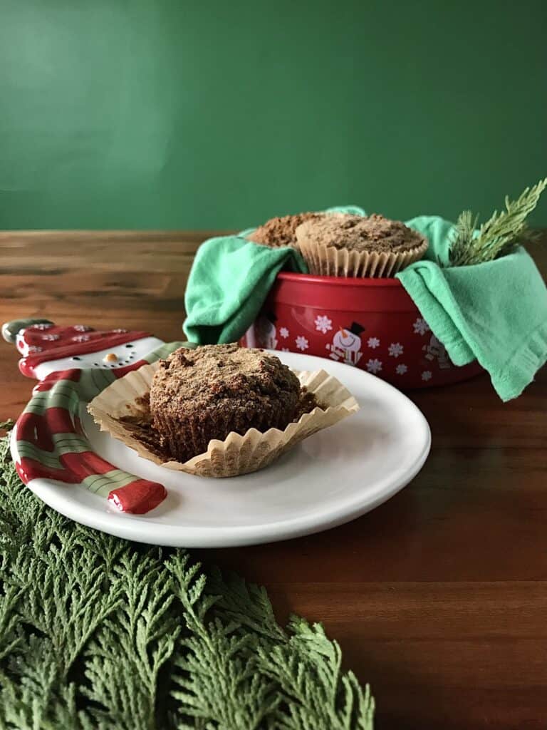 gluten-free gingerbread muffins on a white snowman plate and in a red snowman tin with a green towel