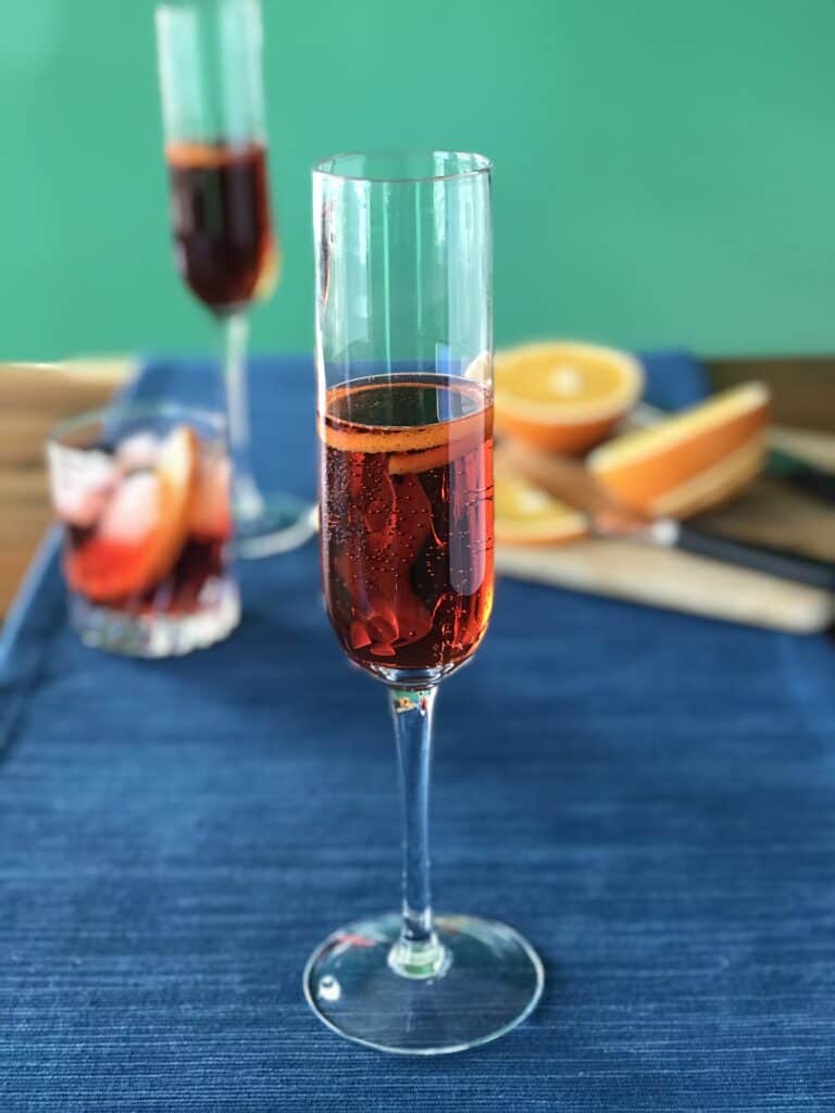 a classic Prosecco cocktail with Campari and vermouth in a champagne flute with an orange peel