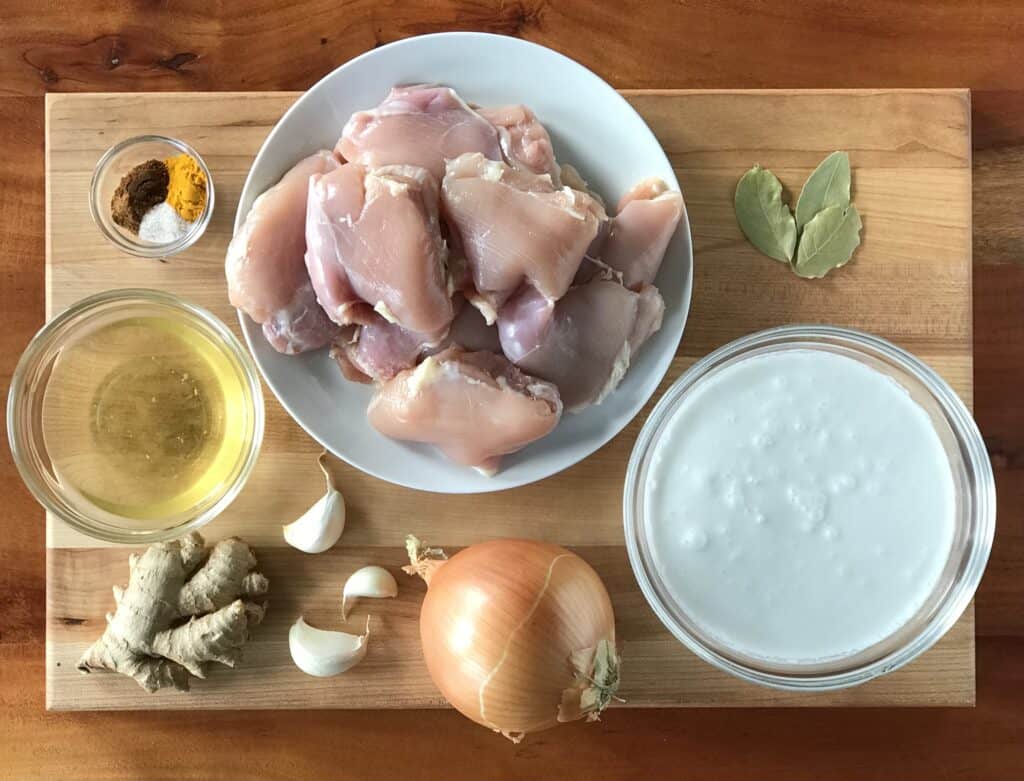 raw ingredients on a wooden cutting board to make a healthy chicken curry