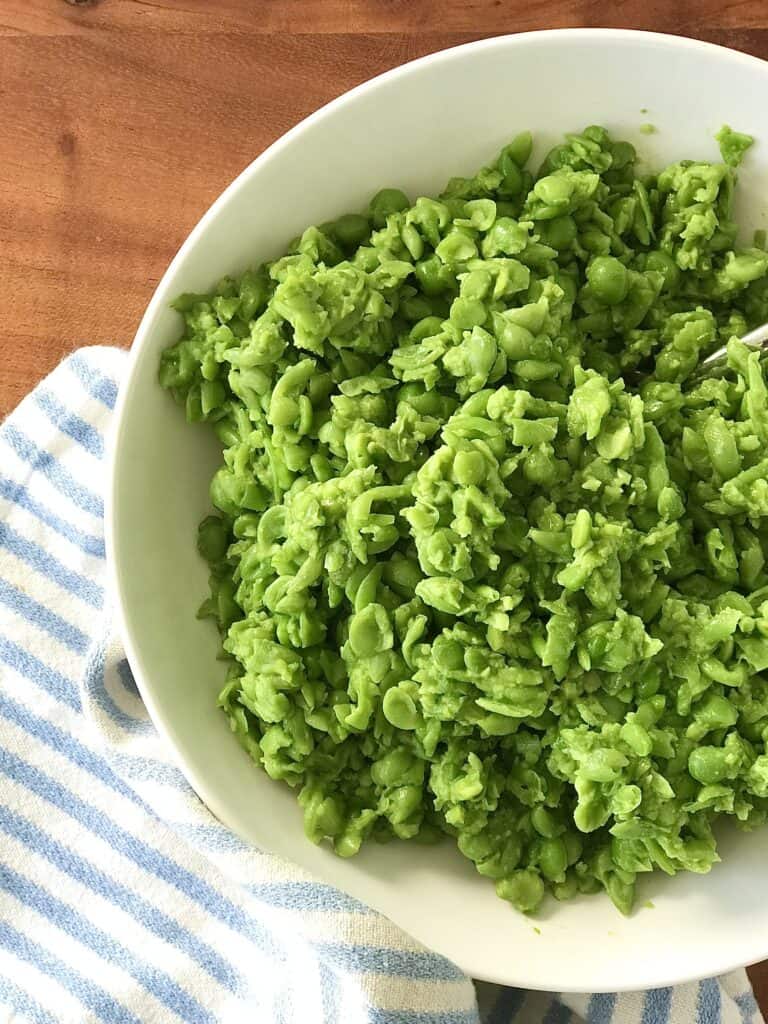a healthy green peas recipe where you mash them and serve in a white bowl on a wood table