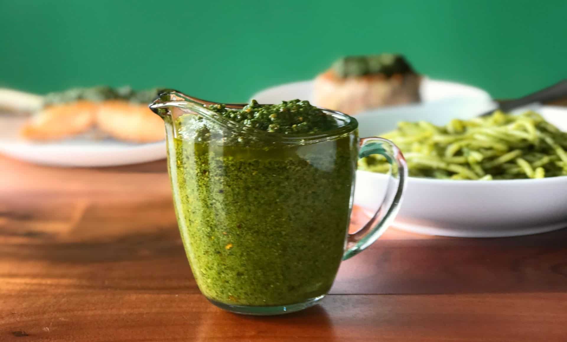 pistachio pesto made with arugula in a small glass pitcher on a wooden table