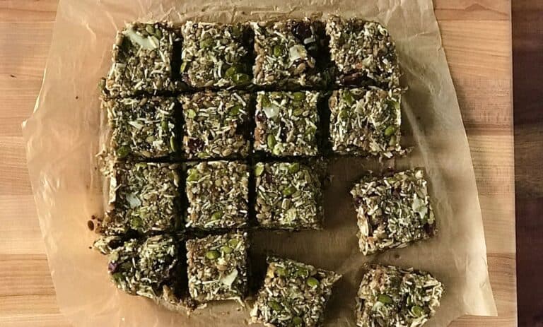 breakfast bars made with dates, seeds and coconut on parchment paper on a wooden cutting board