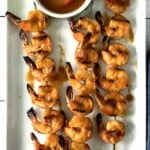 healthy grilled shrimp kebabs on a long white platter brushed with a tangy BBQ sauce