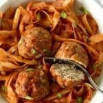 Whole30 turkey meatballs in parsnip noodles coated in tomato sauce, all in a white bowl with a fork