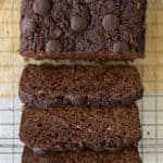 Healthy chocolate zucchini bread sliced on a cooling rack next to a serrated knife