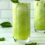 a summer mocktail made with honeydew and mint in 2 tall glasses