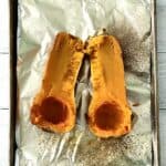 butternut squash roasted on a foil-lined baking sheet, split in half lengthwise and seeded