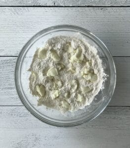 a glass bowl full of paleo pie crust mixture with small blobs of palm shortening throughout