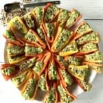 baby peppers filled with guacamole and topped with everything bagel spice mix, arranged on a white plate on a white wooden table
