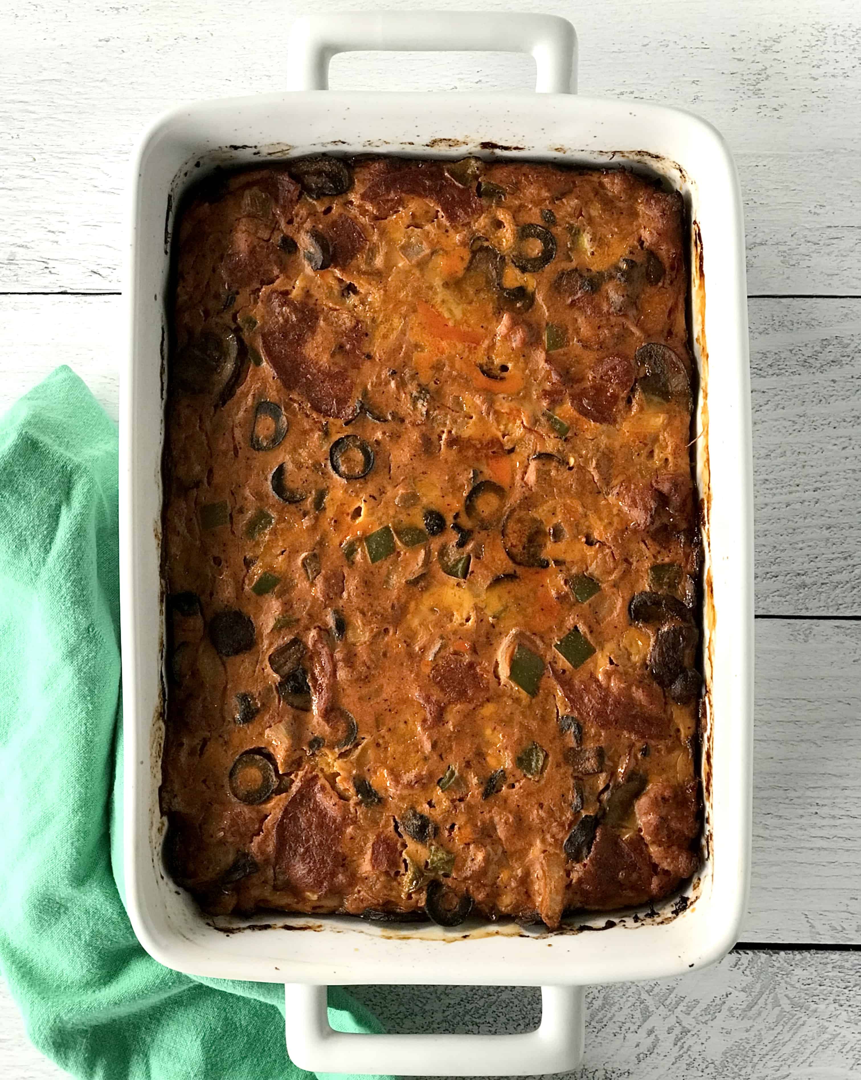 a healthy casserole in a white baking dish next to a green towel