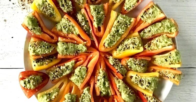 little bell peppers filled with avocado and topped with everything bagel spice mix, arranged on a white plate