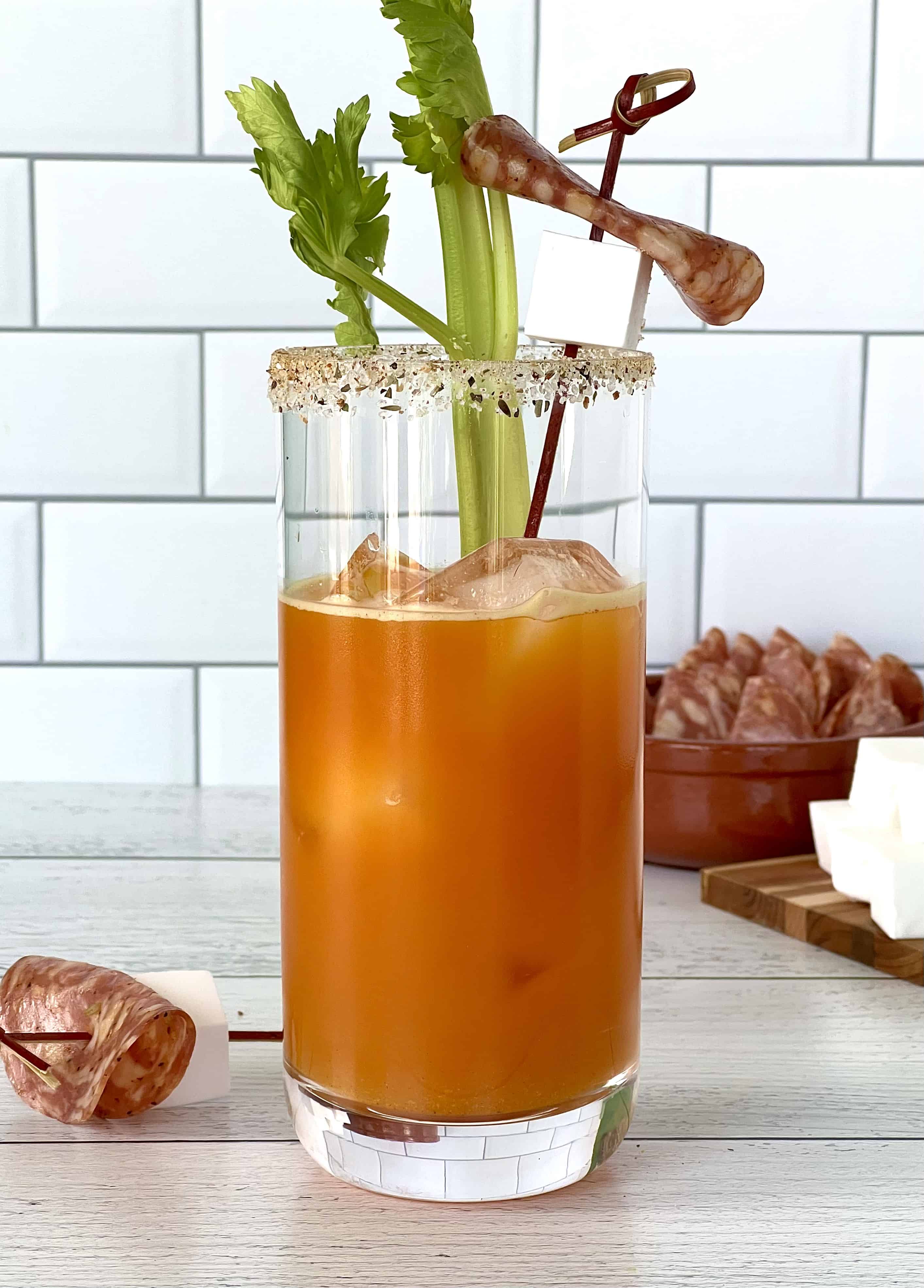 a carrot juice cocktail made with vodka and bloody mary seasonings in a highball glass