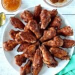 Whole30 chicken wings on a white plate next to bowls of apricot jam and apricot BBQ sauce