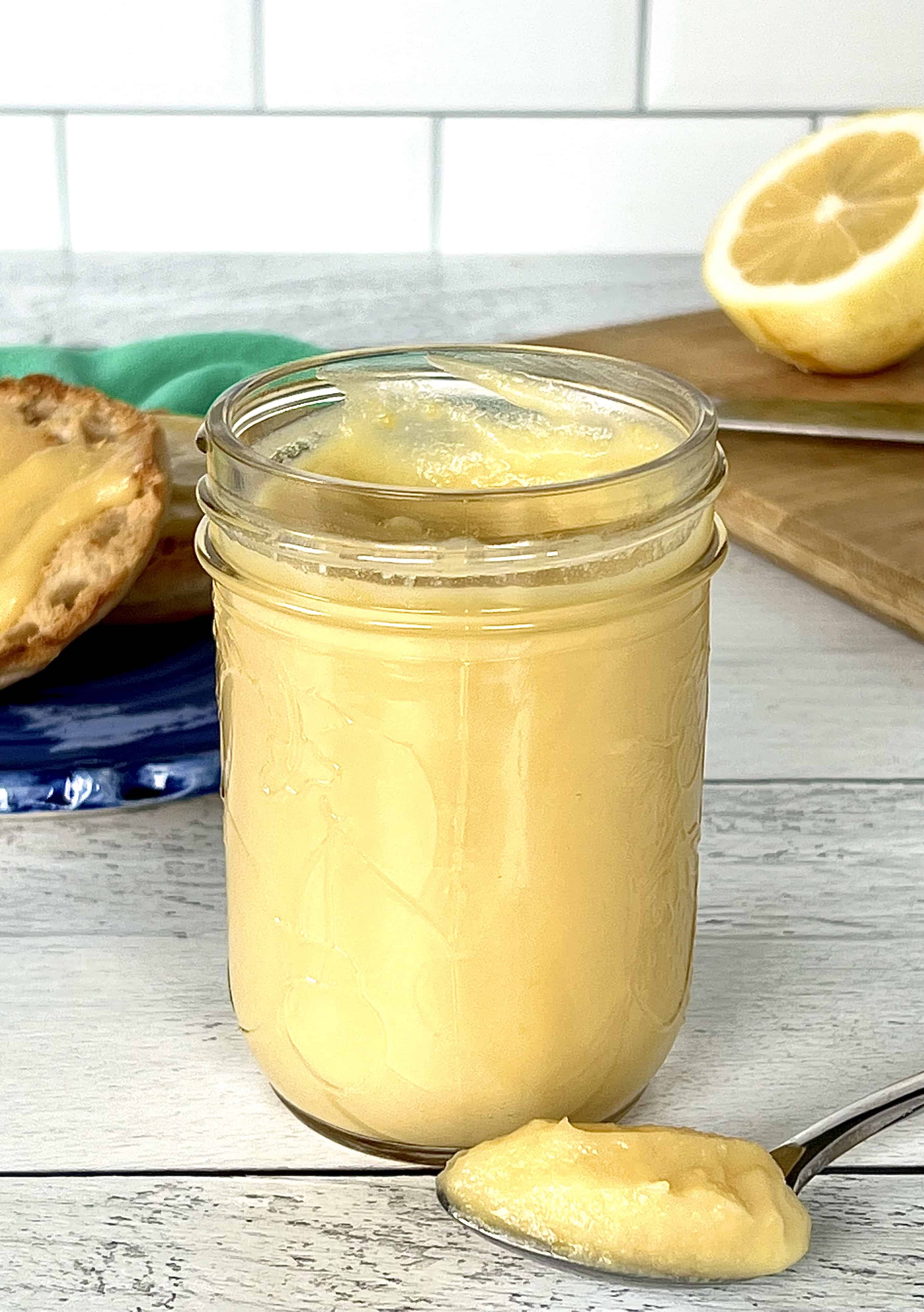 dairy-free lemon curd in a mason jar and on a spoon on a white wooden table