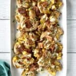 Whole30 smashed potatoes on a long white platter topped with ranch dressing and chopped bacon