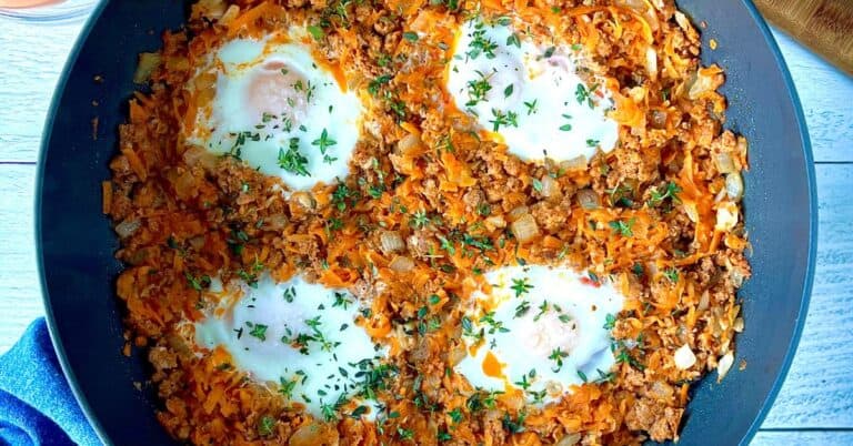 sweet potato hash in a large skillet with 4 eggs topped with fresh thyme