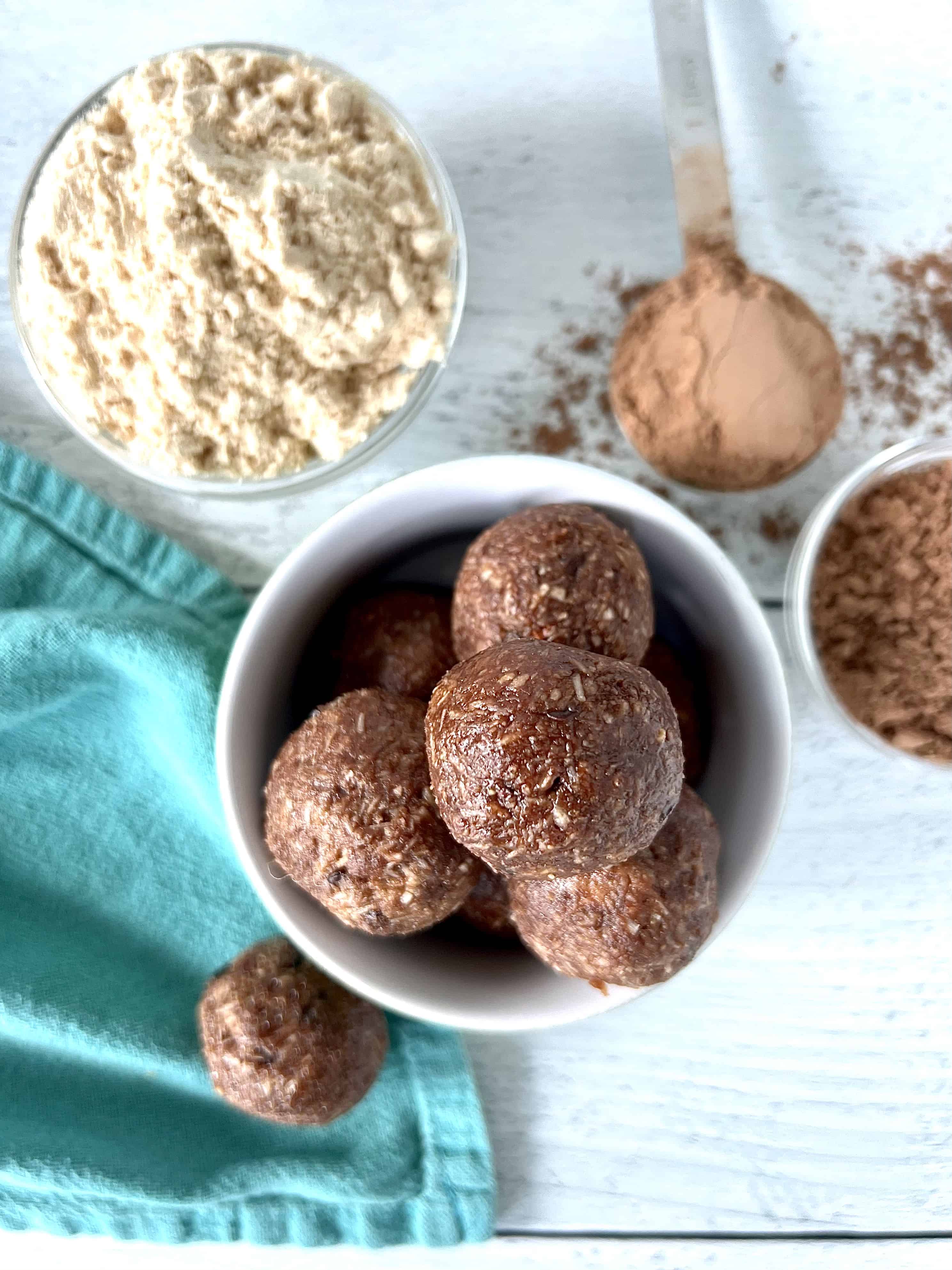 no bake protein balls in a small white bowl on a white wooden table