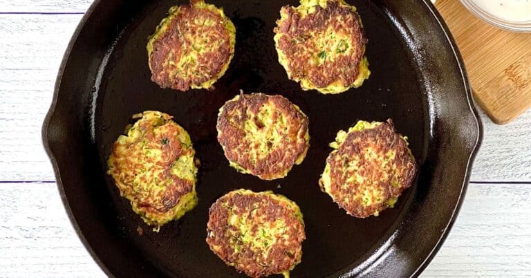 Whole30 zucchini fritters in a cast iron skillet on a white wooden table