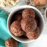 vegan protein balls in a small white bowl on a white wooden table